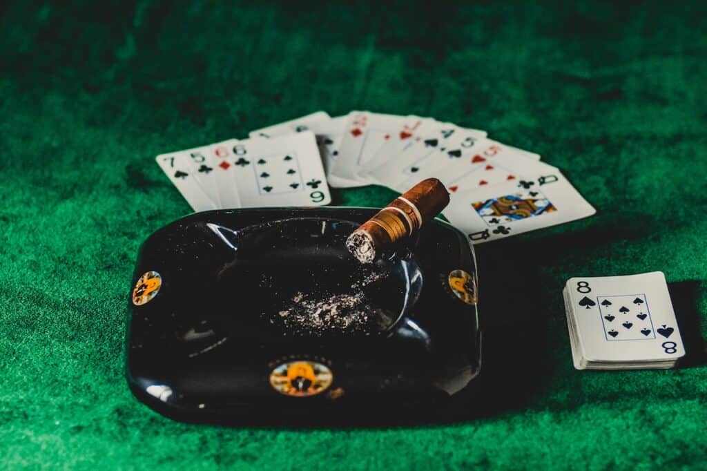 Karte za poker i cigara u pepeljari