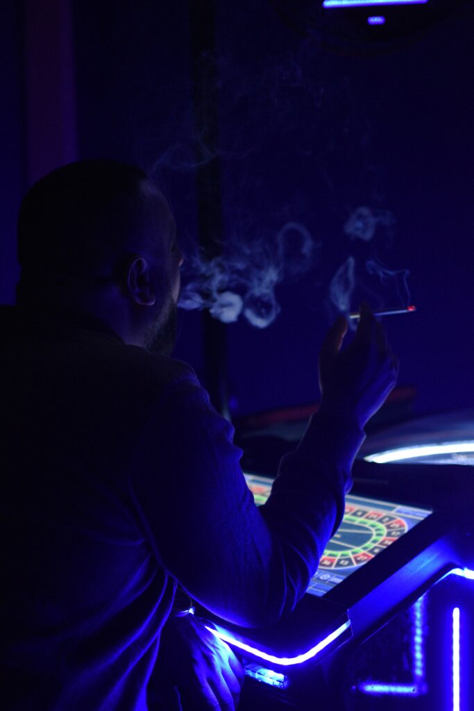 Čovek u kazinu sedi za digitalnom rulet tablom i cigaretom u ruci