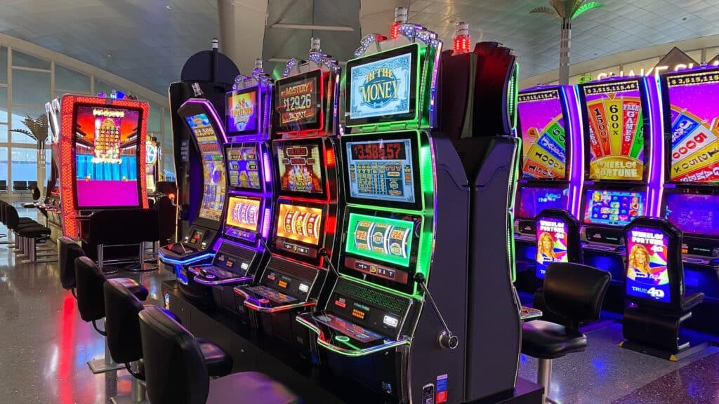 Ambijent kazina u kome su  aparati sa ručkom i 3 svetleća ekrana koji prikazuju dobitke