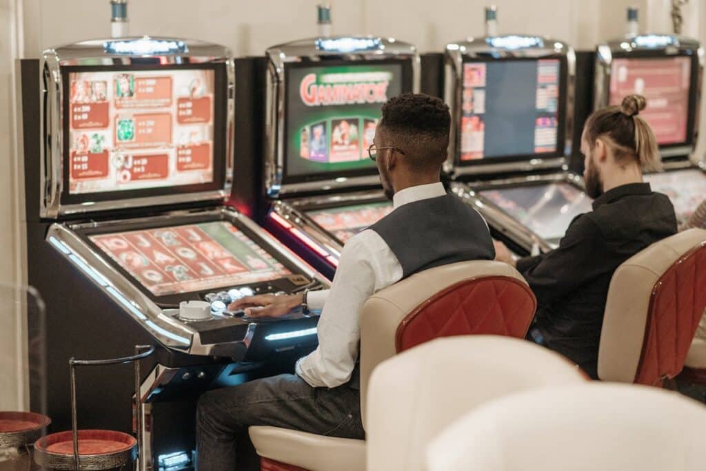 Dva muškarca igraju slot igre na aparatima koji sadrže i Lucky Lady Charm